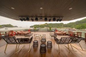 Sunshine Golden Cruises sundeck lounge with cushioned chairs and shelter, overlooking the bay and green hills in Cat Ba