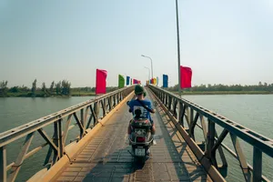 Naik Vespa melintasi jembatan panjang di atas sungai besar di Hoi An dalam rangkaian highlight bertema perahu keranjang bersama Hoi An Backroad Tours