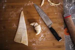 Floured wooden board with cut croissant dough pieces and a chef’s knife during croissant prep at French Cooking Lab in Singapore