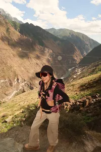 Hiker posing on a rocky ledge on the lesser-known high trail of Tiger Leaping Gorge in Lijiang, with The Bivou Lijiang