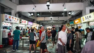 People queueing beneath hawker-centre signs in Singapore on a host-led tour sharing hidden hawker stories with a Nat Geo researcher chef