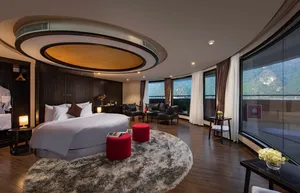 Luxury bedroom on the Oasis Bay Party Cruise with a round ceiling light, bedding and large windows over Halong Bay