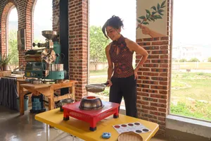 Seeker Yunnan Coffee Estate workshop in Lijiang: woman operates a coffee roaster, with sample tasting plates on a table
