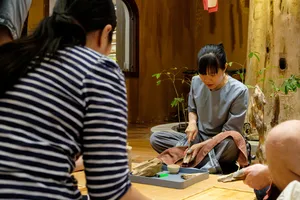 Woman inspects and trims agarwood wood on a workshop table in Hanoi during an Up Travel Vietnam rare agarwood tour