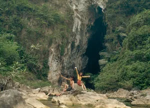 Travellers in Phong Nha’s limestone cliffs and jungle landscape, arms out on a rocky trail during a Greenland Tours outing