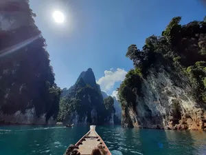 Boat deck with a drink bottle under bright sun, cruising through narrow karst bays in Khao Sok, Cheow Lan Lake