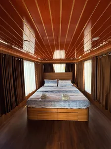 Air-conditioned houseboat cabin in Tanjung Puting, Pangkalan Bun, with neatly made double bed and curtained windows