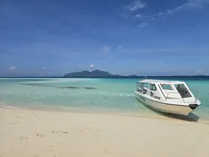 White speedboat resting on a sandy beach in Semporna before snorkel stops on the Bohey Dulang & Islands with Bigfin Divers