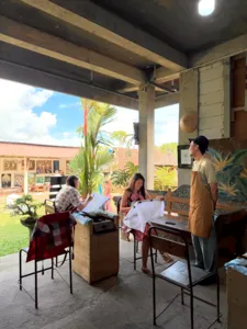 People in an open-air workshop at Five Arts Studio painting batik-inspired designs inside the garden hall in Ubud