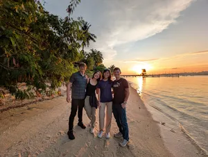 Travellers walking along a calm Singapore beach at sunset during a 2D1N farmstay by the sea with The Unexpected