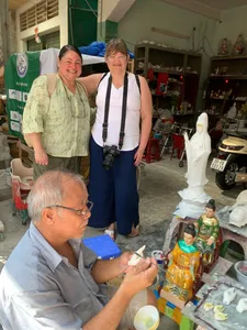 Tour visitors browse a stall of ornate white statues and figurines in a craft market in Ho Chi Minh City with Viet Awesome Tours