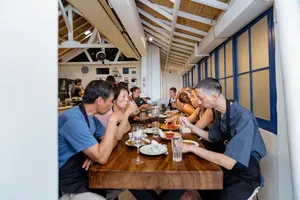 Gili Islands cooking class in Lombok: group dining at a long table, enjoying the dishes they've just learnt to cook