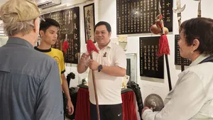 Martial arts class in Ho Chi Minh City Lion Dance heritage room, as a guide holds a wooden staff and demonstrates to guests