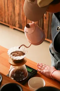 Hands pouring coffee from an electric kettle into a cup during a small-batch brew at Seeker Yunnan Coffee Estate, Lijiang
