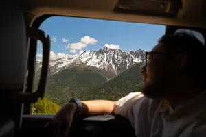 Traveller gazing from a vehicle window at snow-capped peaks near Shangri-La during a 6-day Loop with a Tibetan guide