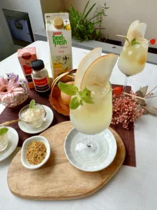 Pouring-ready TCM-inspired mocktails on a round wooden board, with citrus, mint leaves, and dried herbs beside—workshops in Singapore