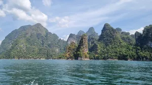 Green rainforest covering limestone towers across the lake, captured from a boat on Khao Sok National Park