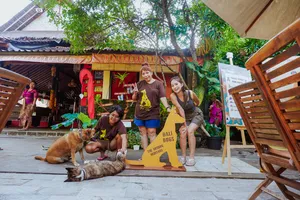 Visitors and staff pose with dogs beside a “BALI DOGS” sign at a Bali conservation centre run by Bali Conservation Adventures