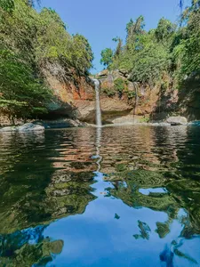 Wide view of a waterfall dropping into a calm pool surrounded by trees in Khao Yai National Park outdoors
