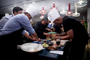Teams plate dishes in Singapore during the local produce cooking challenge, chefs supervise at long tables — workshops in Singapore
