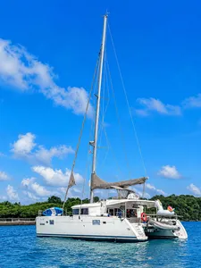 Zen Sea catamaran sailing on the calm waters off Singapore, with bright blue sails under a clear sky