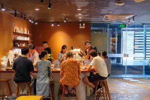 Group gathered around tables as a guide explains rare agarwood scent in the workshop café in Hanoi, Vietnam