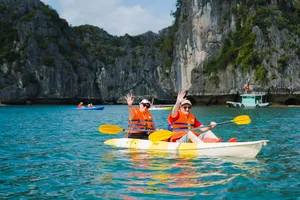 Kayakers in orange life jackets paddle through calm waters near limestone karsts on a Cat Ba cruise