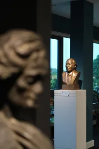 Bronze bust sculpture on a pedestal inside Quang San Art Museum, with a blurred stone artwork in the foreground, Ho Chi Minh City