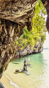 在兰卡威丹绒鲁平静水面上玩立式桨板的人们,跟随 H2Ocean Langkawi 沿着隐秘海滩划行,穿过岩石峭壁下方