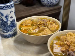Two bowls of savoury Vietnamese soup with meat and herbs on a table during a Hanoi street food adventure