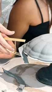 Ina Atelier potter hand-trimming an antique European-style ceramic plate during pottery workshops in Singapore