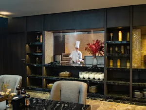 Chef in a luxury restaurant of Doris Cruise presenting breakfast at an open buffet with warm lighting in Halong Bay