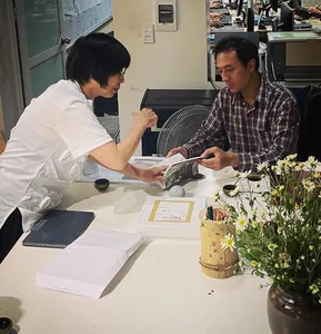 Two people reviewing papers at a meeting table, preparing a host-led Hanoi collective housing walk