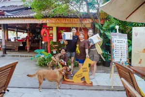 Group photo with rescued dogs and printed information boards in the courtyard of a Bali Conservation Adventures shelter in Bali