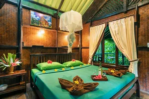 Cozy cabin bedroom with made beds and mosquito netting at Khao Sok Riverside Cottages, family-run cabin stay in Khao Sok National Park