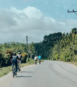 Cyclists riding a quiet road through greenery near Khao Lak on a half-day biking route with Hands Experiences Thailand