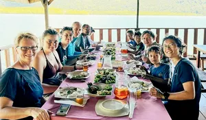 Meal shared by travellers at a long table on the deck during a Langkawi trip for mangroves, caves and island swimming