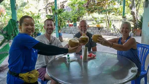 Snack break on a Mekong Island bike tour from Ho Chi Minh City, as travellers share fruit drinks at an outdoor table