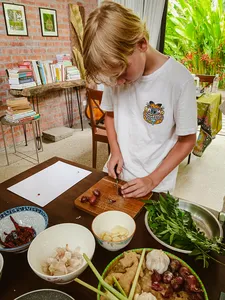 Chopping fresh herbs for Malaysian comfort food at a Kebun Lidstari kitchen prep table in Langkawi farmhouse