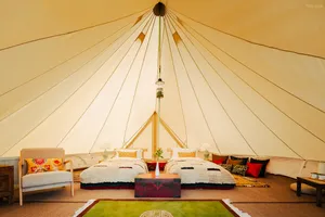 Glamping tent interior at Ferme Liotard in Shangri-La with two covered beds, central rug and a hanging light under canvas