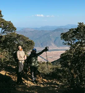 Hikers with trekking poles on a forest trail above Lijiang during a guided hike to the 1st Peak of Jade Dragon Snow Mountain