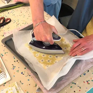Hands ironing patterned cotton on a work mat to shape reusable food wraps for teams in Singapore during workshops in Singapore