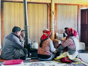 Group chatting around a tea setup on patterned mats inside a guesthouse in Lijiang during the Yi & Naxi village trek