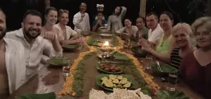 Retreat group sharing dinner around a long table with candles and plates under a shaded pavilion at Omunity Bali, Bali