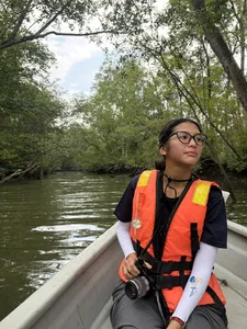 Young Nautilus guide with a life jacket and camera on a river boat through lush greenery near Johor Bahru during the Orang Seletar tour
