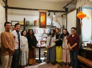 Sekelompok orang berkumpul di ruang perpustakaan yang nyaman di Chan Dat Living Room, Hoi An, dikelilingi rak, lampu lentera, dan buku saat menikmati pengalaman budaya yang mendalam