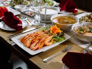 Cat Ba cruise dinner with grilled prawns on a platter, surrounded by bowls of soup and salads on the table