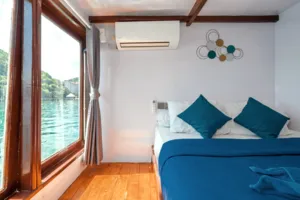 Onboard cabin on a phinisi with a window framing calm water during a private 3D2N Komodo cruise, near Labuan Bajo