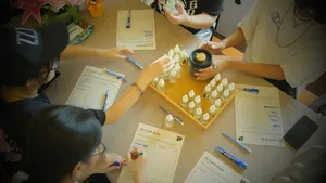 Measuring fragrance drops into small coco-soy candle jars on a table at Perfume Play in Singapore during a candle workshop