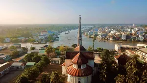 Aerial view of a Mekong Delta river town with a tall church spire, on the Ho Chi Minh City to Mekong transfer